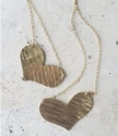 two textured gold heart chain necklace on white distressed background