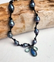  peacock pearl necklace knotted on black leather with labradorite, green quartz pendant on wood.