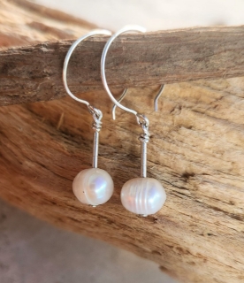 silver hoop white pearl earring on stick against wood background