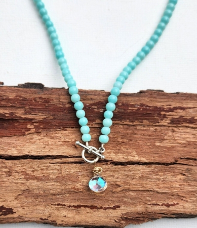 aqua blue beads surround rainbow quartz pendant necklace on wood