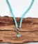 aqua blue beads surround rainbow quartz pendant necklace on wood