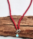 close up o rainbow quartz necklace with deep pink beads on wood