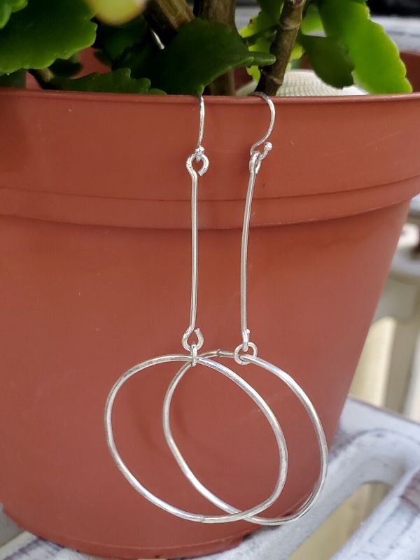 long silver hoop stick earrings on clay pot