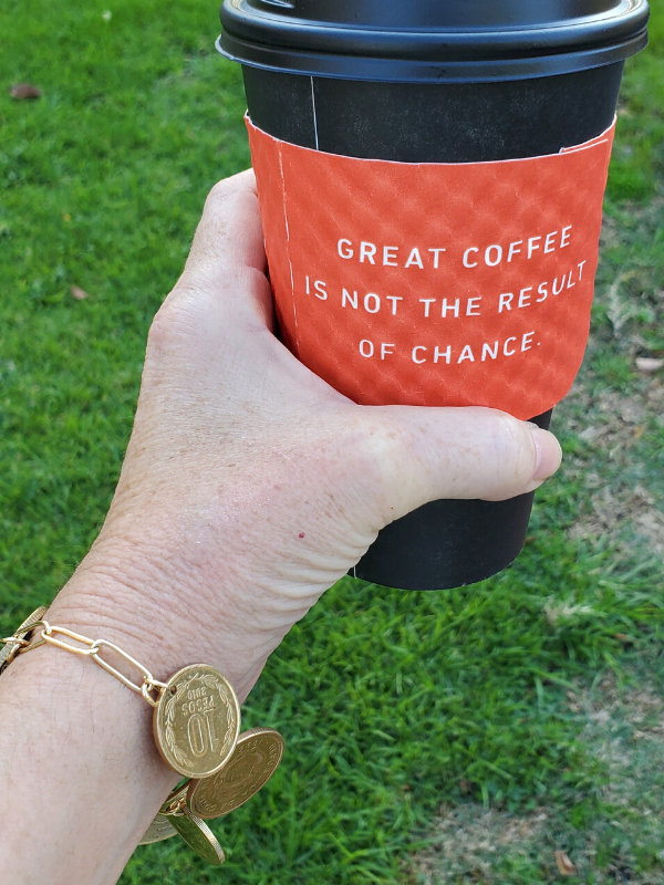 holding coffee & wearing chunky coin bracelet