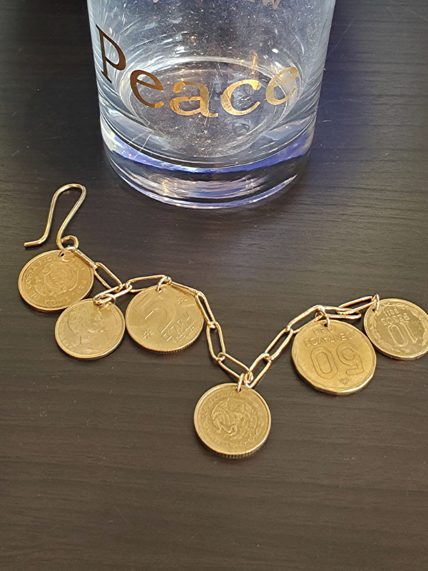 coin charm bracelet by glass that says peace