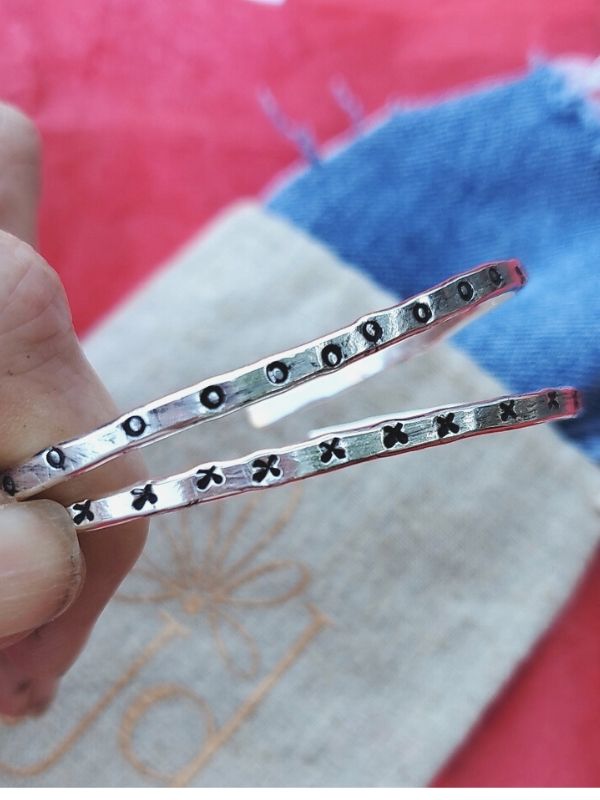 fingers holding silver XOX bracelets