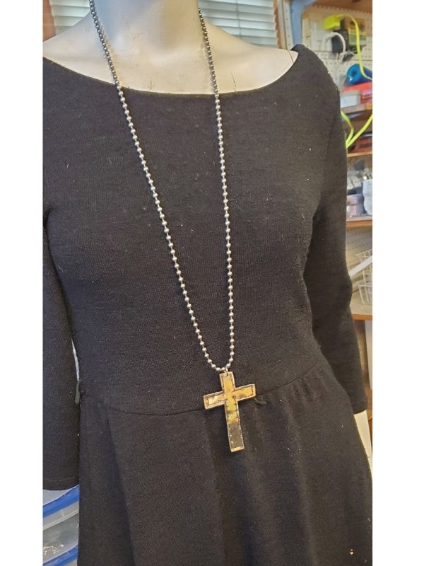 mannequin with black dress and long cross necklace
