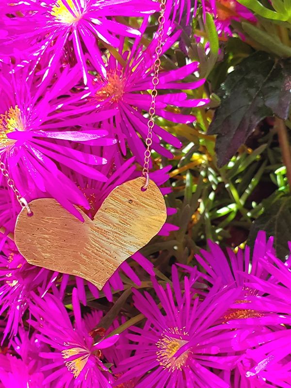 Gold heart necklace in flower bush
