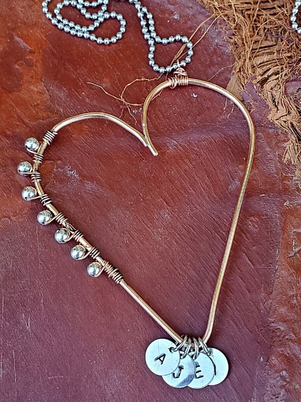 mixed metal heart necklace on palm frawn
