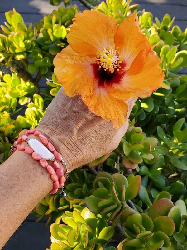 pink gemstone bracelet on wrist with hibiscus flower