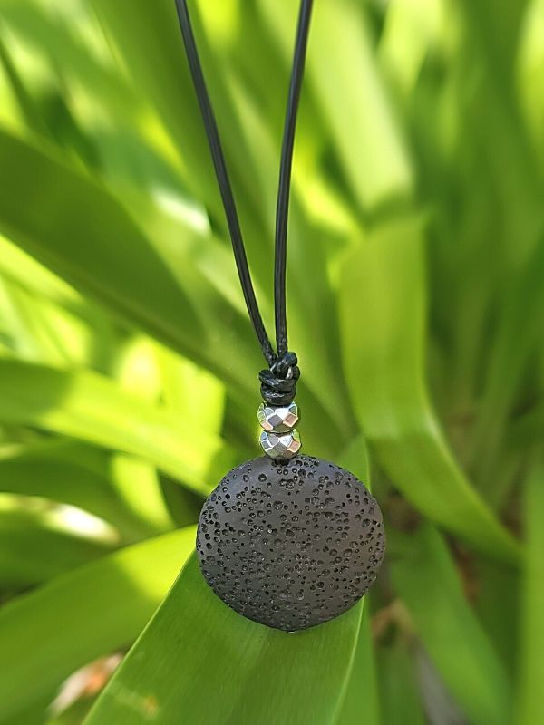 black lava necklace hanging in plants