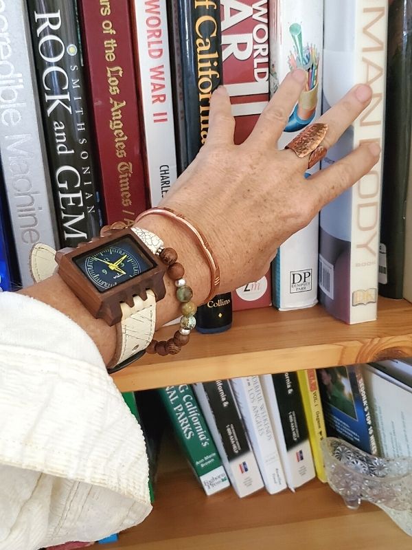 Mistura watch & bracelet on arm touching books