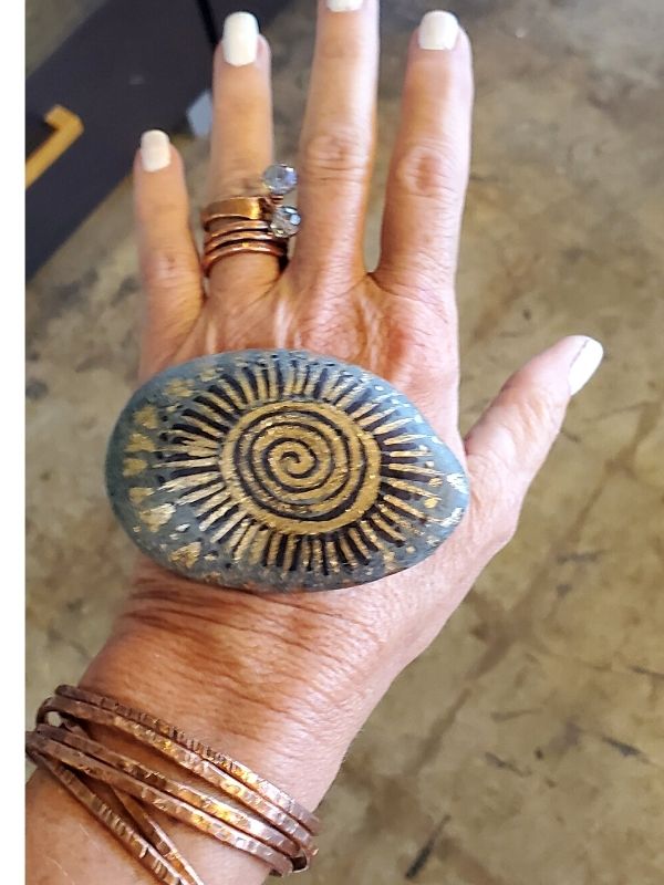 copper jewelry & painted rock on hand