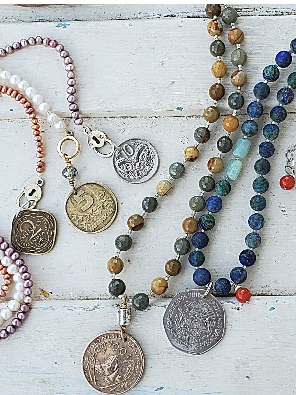 Variety of beaded gemstone coin necklaces displayed on white trunk