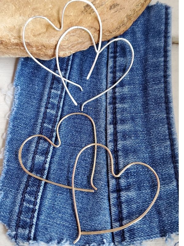 silver & gold heart hoop earrings laying on denim