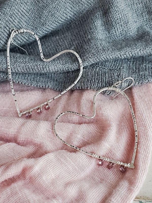 big silver heart earrings on pink & gray clothing