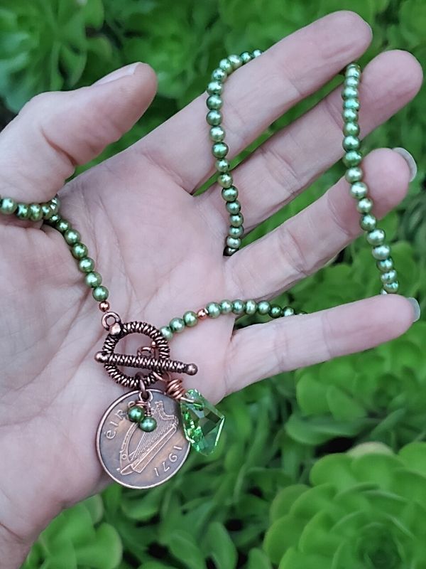 irish Coin necklace in hand in the garden