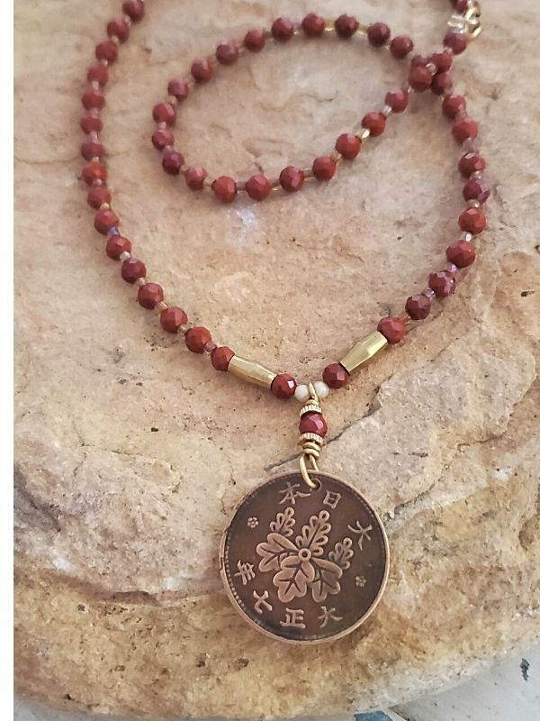 Japanese coin red gemstone coin necklace on rock