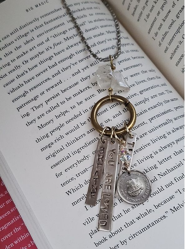 Word s charm necklace on a book
