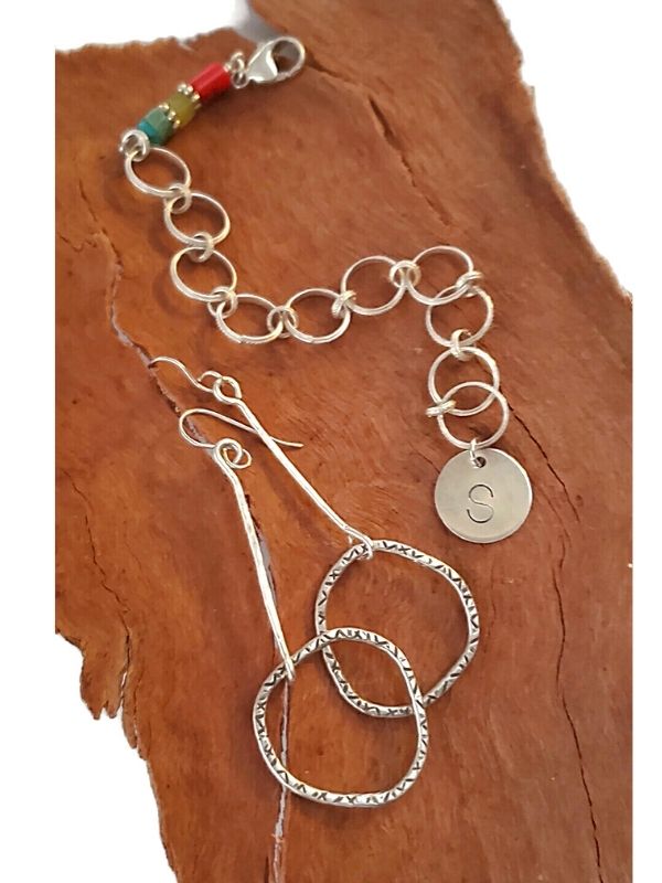 silver earrings and charm bracelet on wood