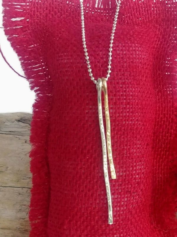 silver gold stick necklace on red pillow
