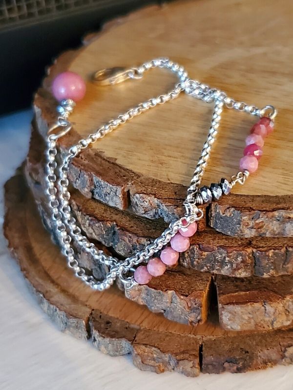 pink gemstone silver chain bracelet on stack of stones