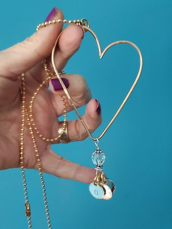 fingers holding brass hammered open heart necklace