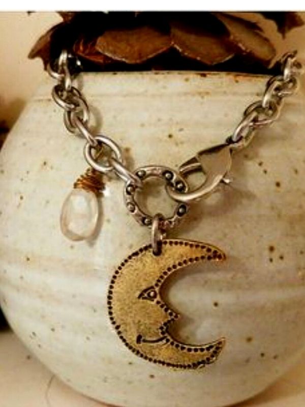 moon necklace on ceramic display with pine cones