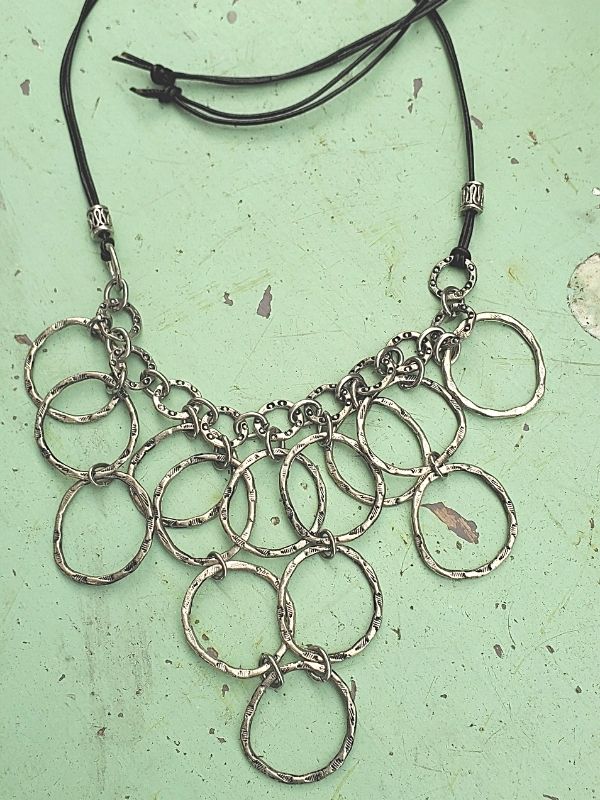 silver circle bib necklace on green background