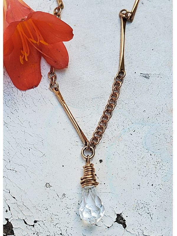 clear crystal bar necklace on white with orange flower