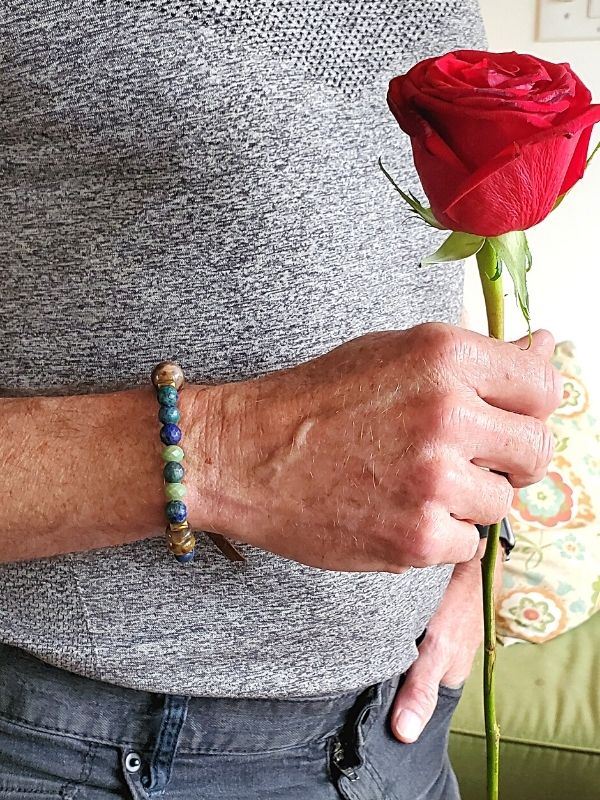 male wearing blue bracelet holding red rose