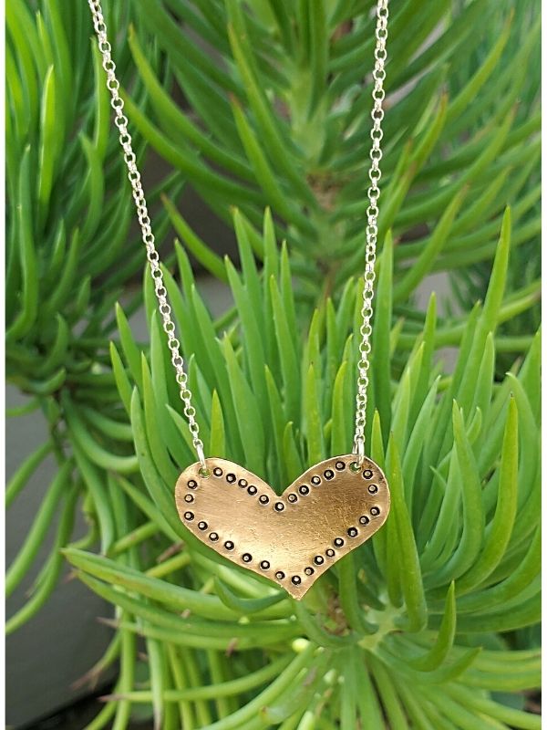 bronze heart necklace hanging from plants