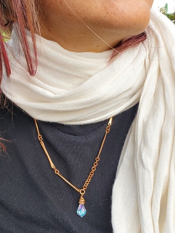 wearing white scarf with longer bronze crystal necklace