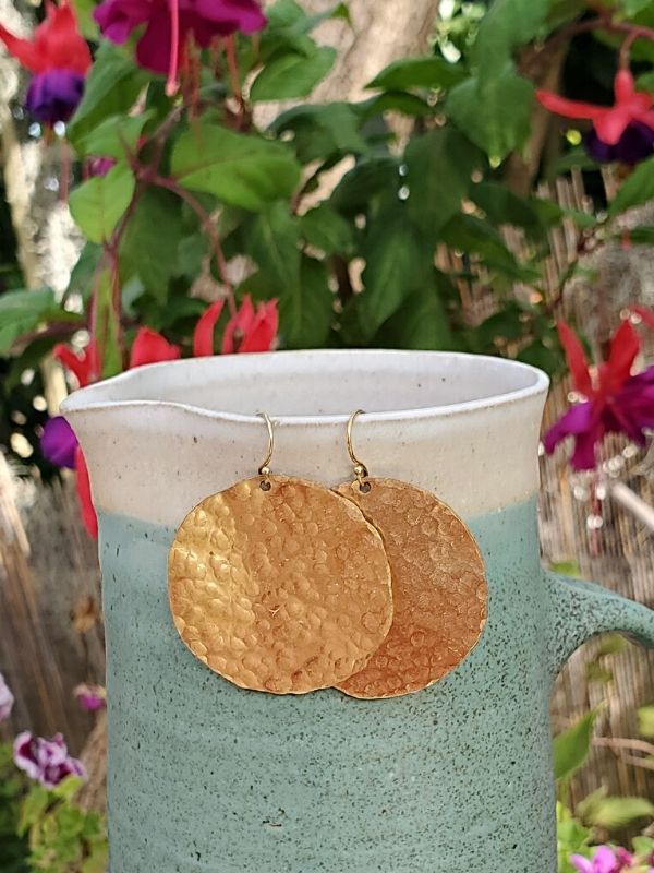 big gold disc earrings on ceramic pitcher
