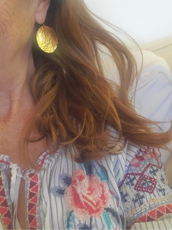 wearing big gold disc earring with embroidered peasant top