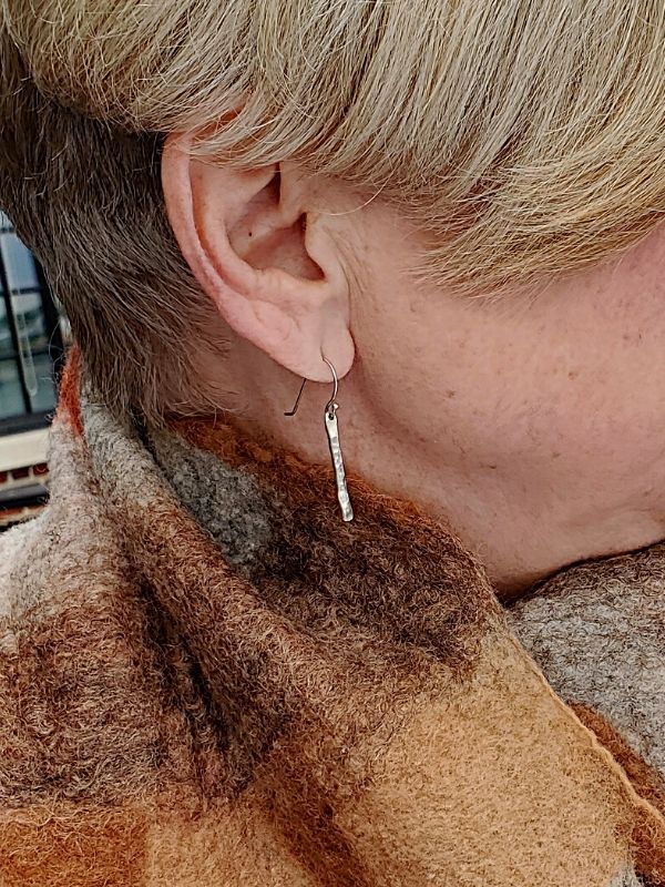 female profile wearing silver stick earrings