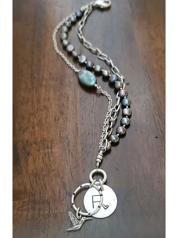 peals ,chain, initial & hummingbird charm bracelet on wood