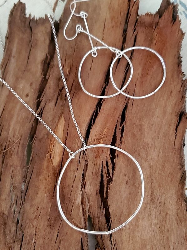 silver circle necklace earrings on wood