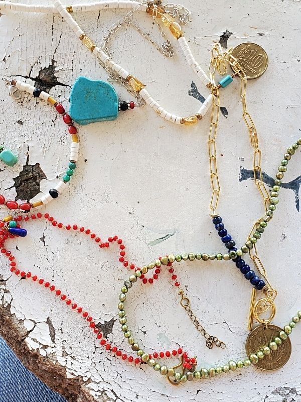 colorful gemstone necklace array on white table