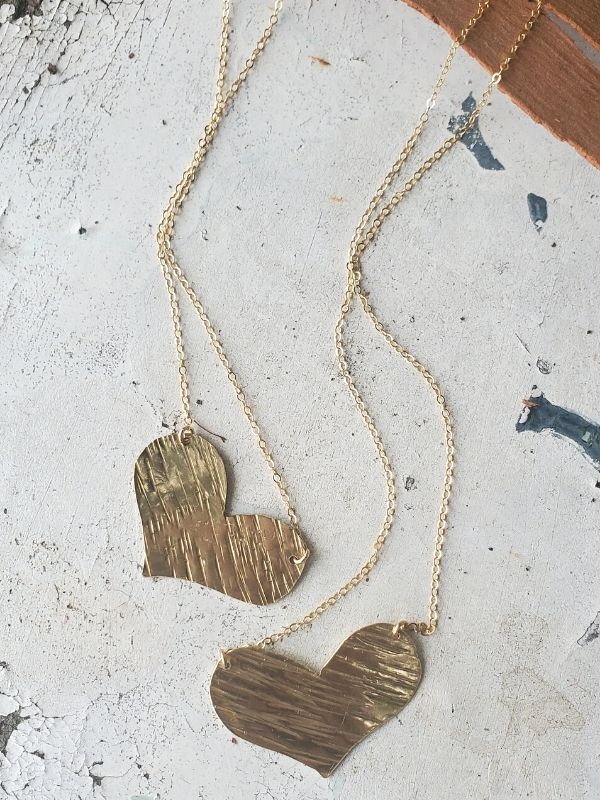 2 gold artisan heart necklaces on table