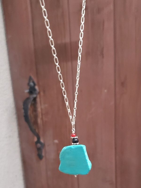turquoise necklace near wood door