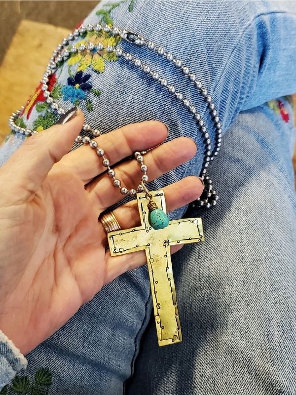 holding a long cross necklace