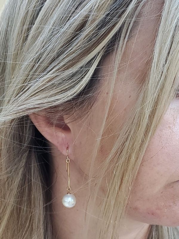gold stick white pearl earrings on female profile