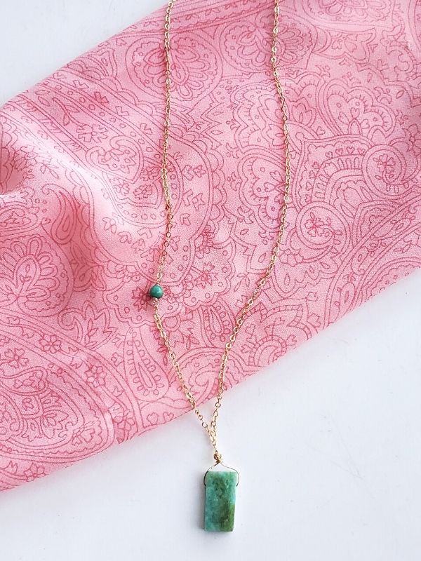 green gemstone gold chain necklace on pink top