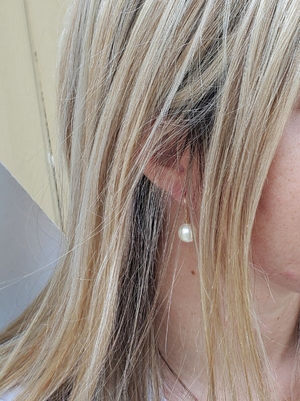 single white pearl earring hanging on ear with long hair