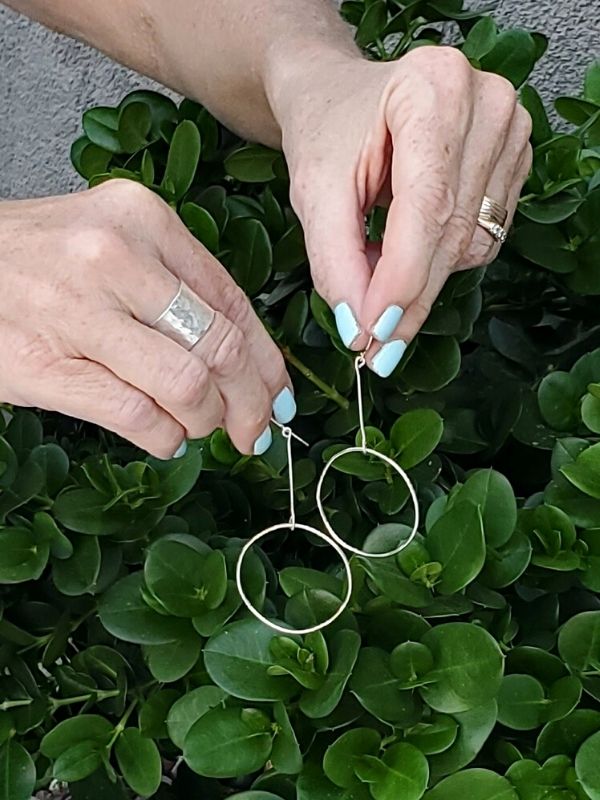 holding silver hoop stick earrings