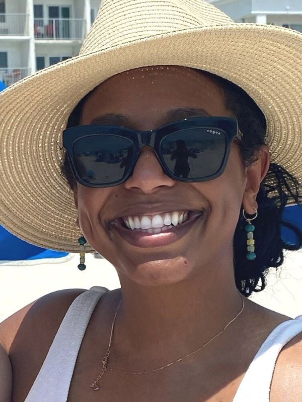 female wearing green earrings & beach hat