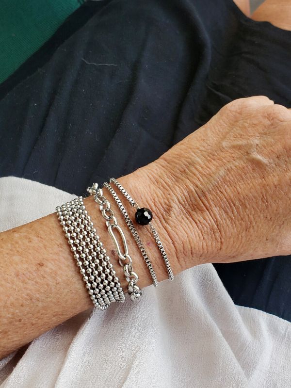 wearing a stack of three silver chain bracelets