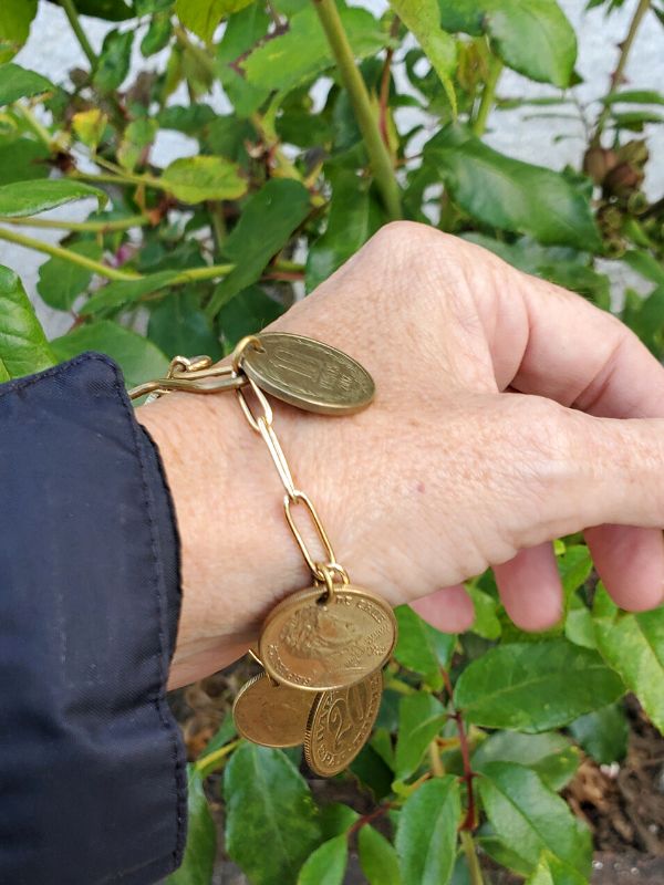 old coin charm bracelet on wrist