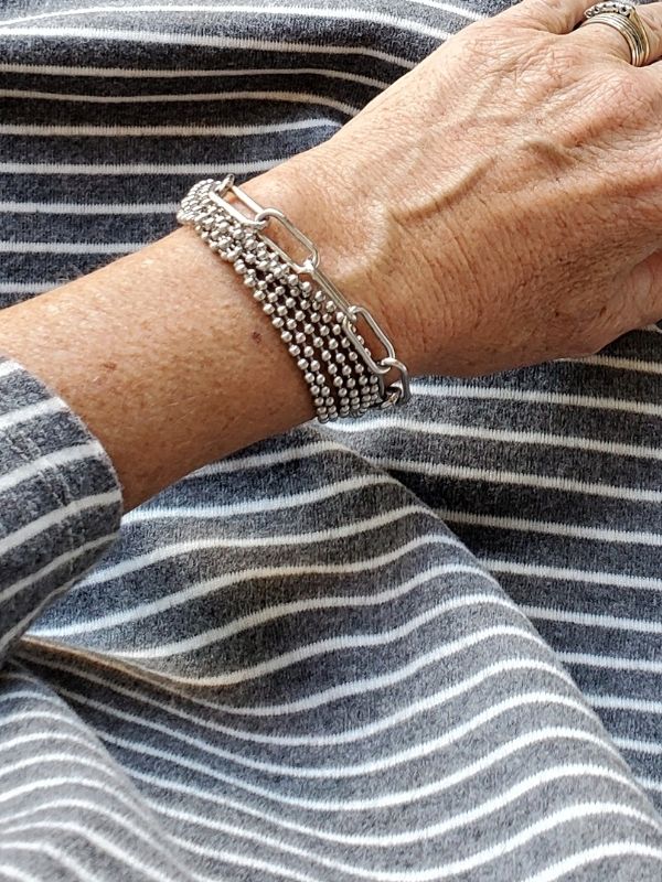 2 silver bracelets worn with gray outfit